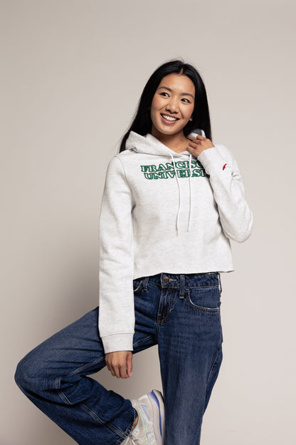 Person wearing a white hoodie with text and blue jeans on a plain background